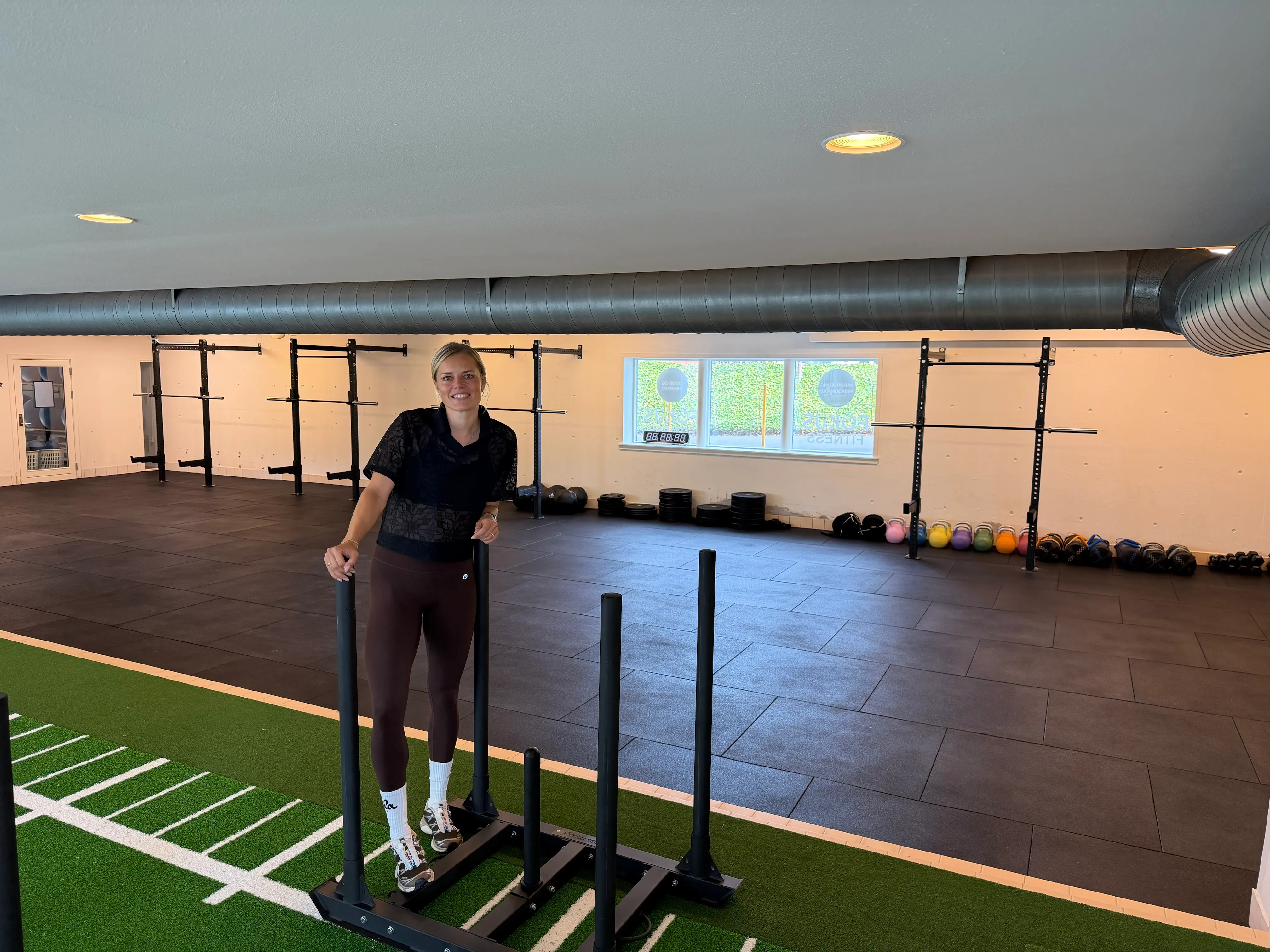 Træningsområdet hos Fitness Aalborg med kunstgræsbane, sled, racks og kettlebells